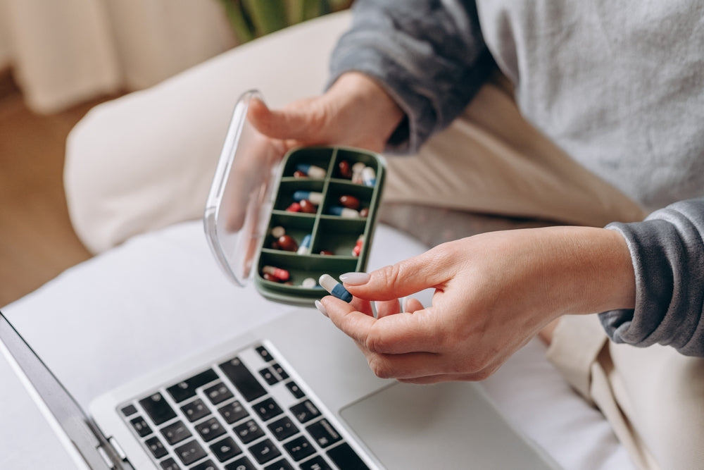 Female hand holding her vitamins and supplements, variety of pills and capsules an glass of water